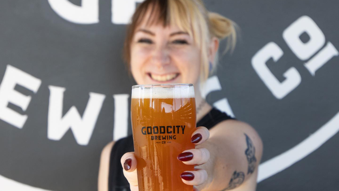 woman holding beer that says "Good City Brewing"