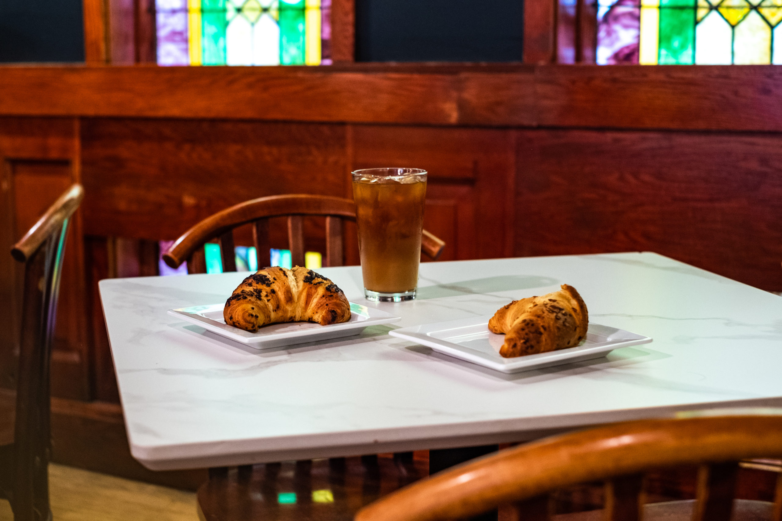 Two croissants and an iced coffee on a marble tabletop at Vendetta Coffee in Wauwatosa