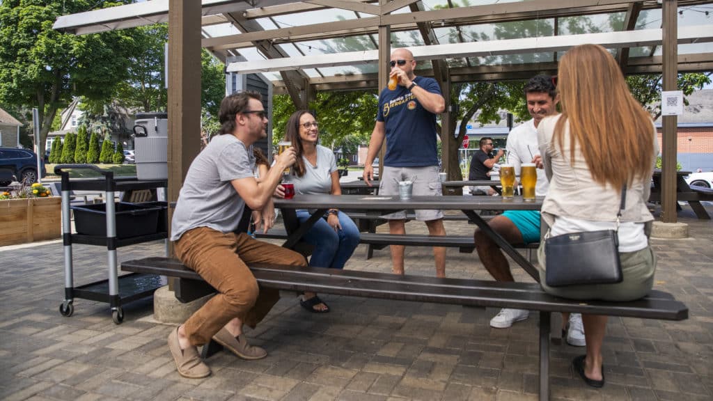 Group of people gathered around a picnic table drinking beer at Lion's Tail Brewing in Wauwatosa, WI 